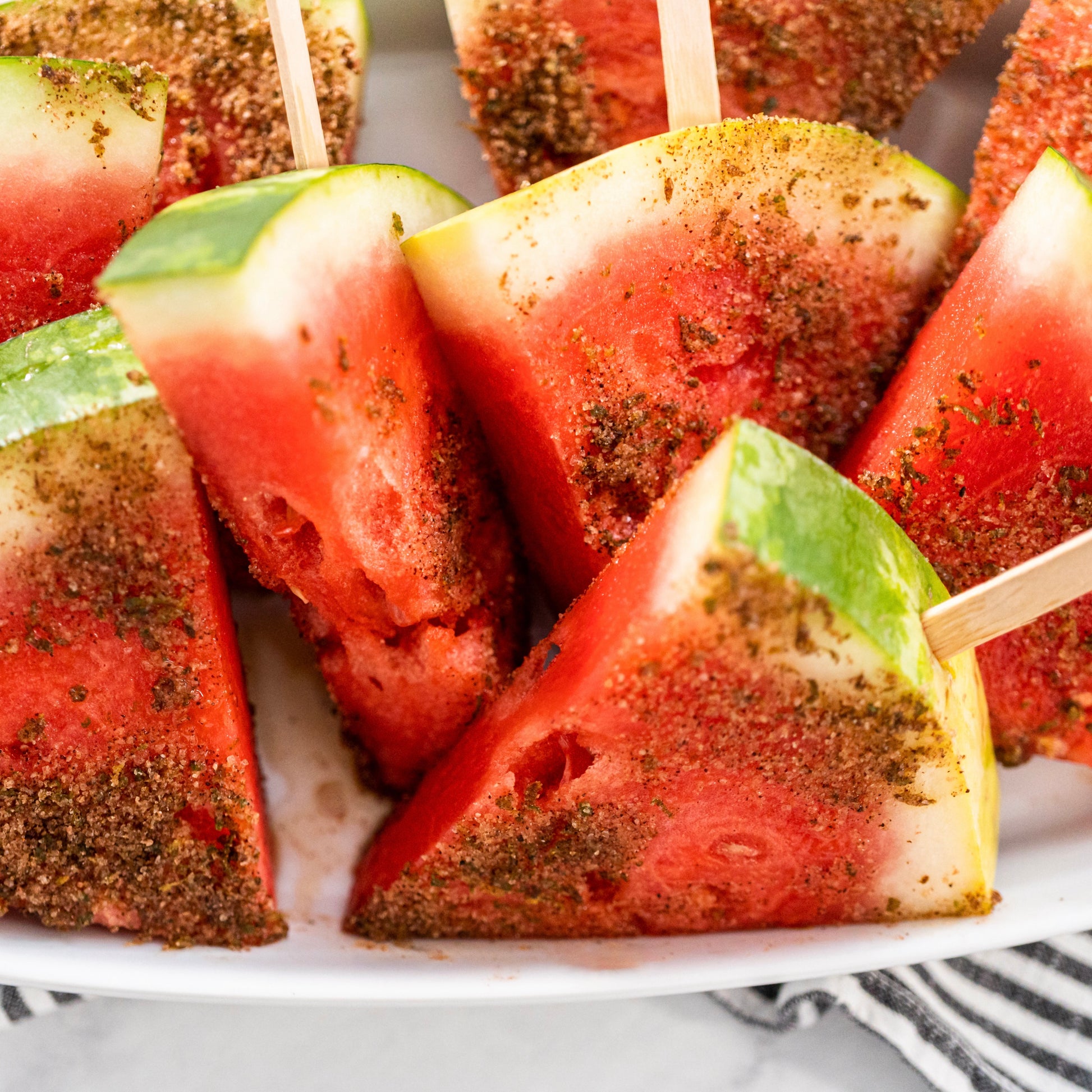 Watermelon skewers with seasoning on a white plate