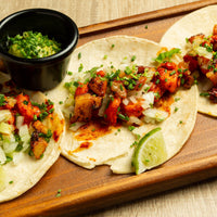 Tortillas with chicken and vegetables on a wooden board with a side of guacamole.