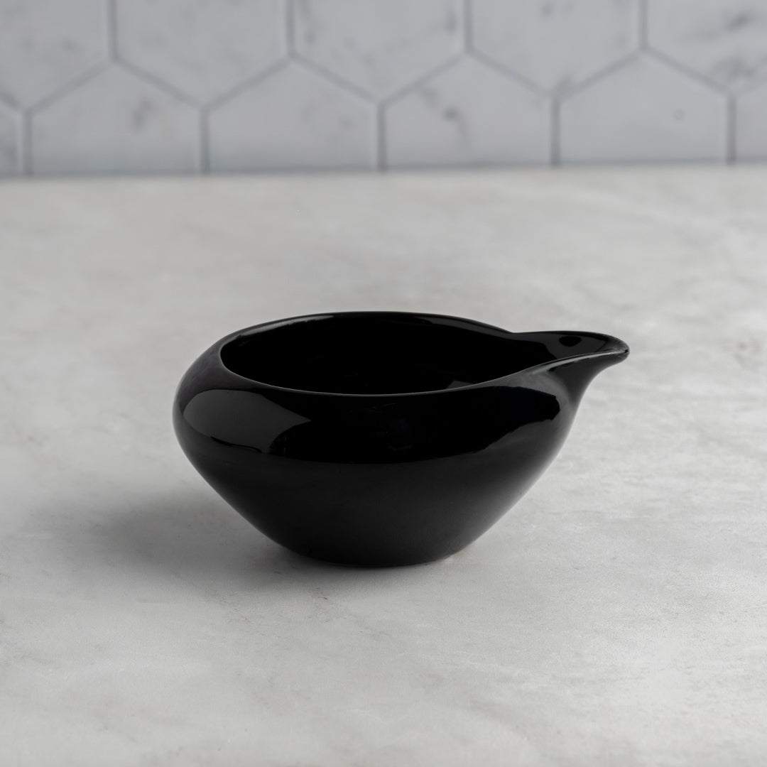 Black ceramic bowl on a marble surface with a gray tiled wall background