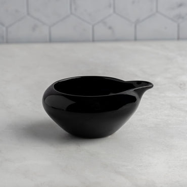 Black ceramic bowl on a marble surface with a gray tiled wall background