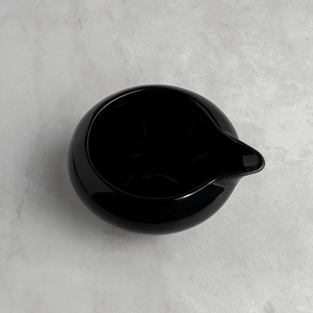 Black ceramic pitcher on a gray concrete surface
