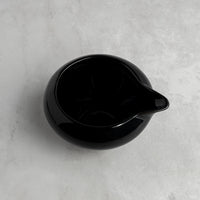 Black ceramic pitcher on a gray concrete surface