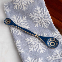 Blue wooden spoon with decorative handle on a snowflake-patterned towel