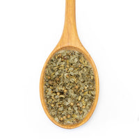 A wooden spoon filled with dried green herbs and spices, shown from a top-down view on a plain white background.