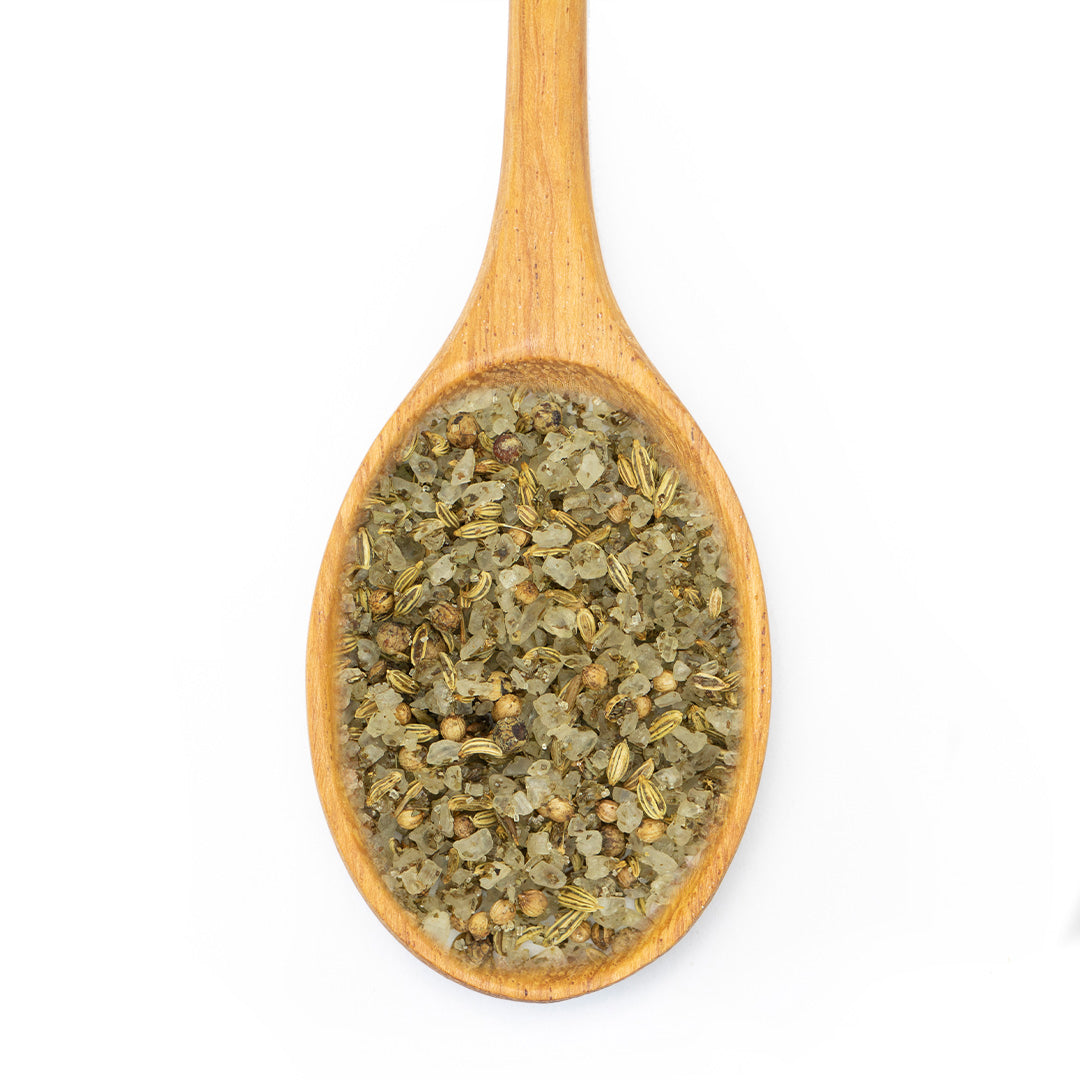 A wooden spoon filled with dried green herbs and spices, shown from a top-down view on a plain white background.