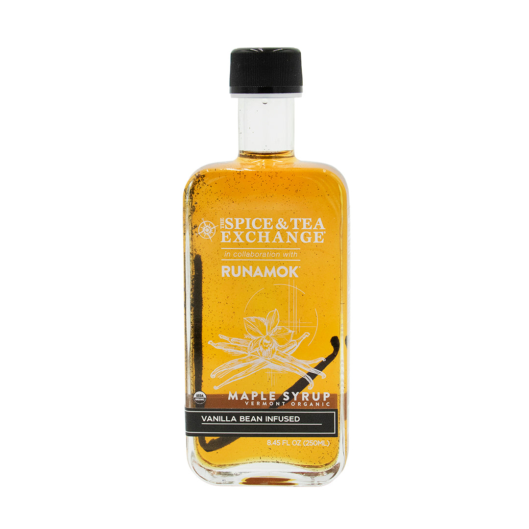 A bottle of Spice & Tea Exchange Runamok maple syrup with vanilla bean infusion, featuring golden-amber liquid inside a clear glass bottle with a black cap, set against a plain white background.