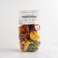 A package of Pappardelle-Primavera pasta by The Spice & Tea Exchange, featuring multicolored dried pasta pieces visible through a clear bag with a white header card.