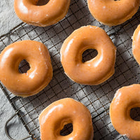 Glazed donuts on a cooling rack with a textured surface background