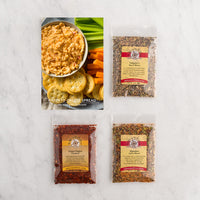 Three baggies of seasonings arranged on a white marble surface with a recipe card showing pimento cheese spread with crackers and celery.