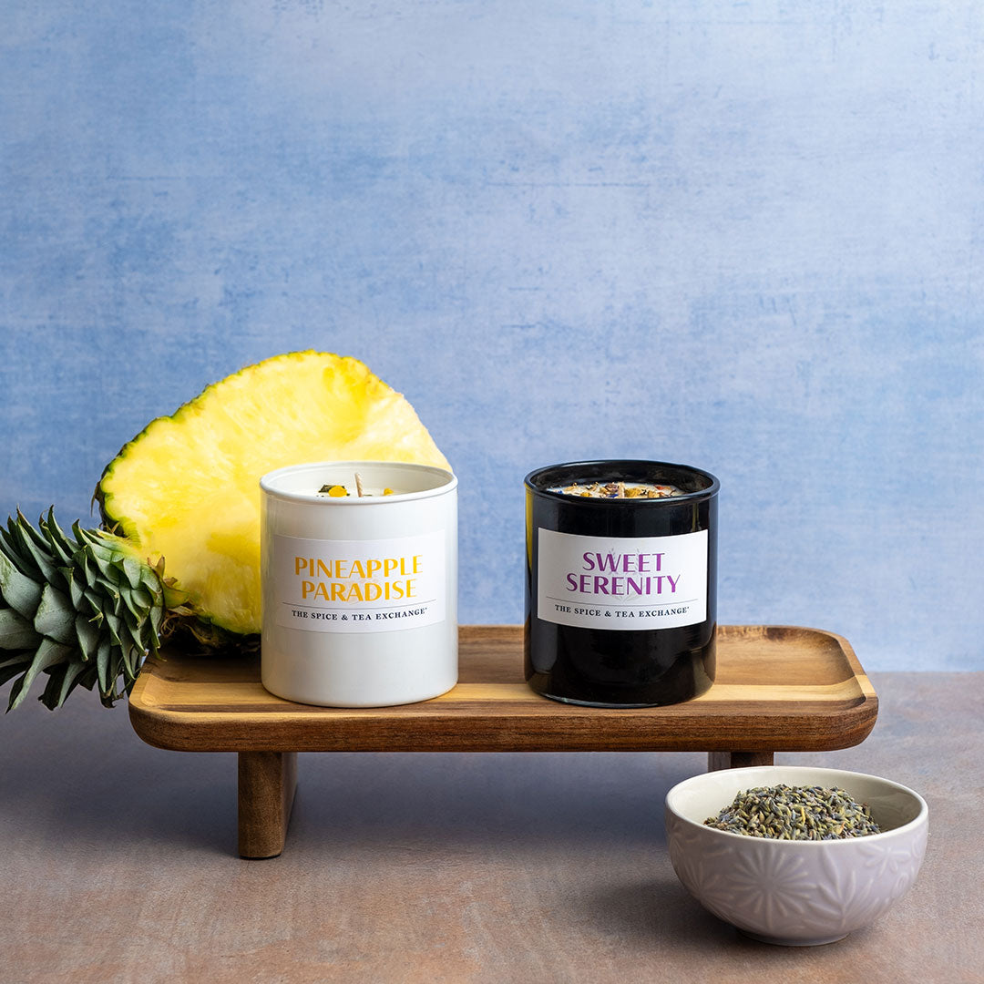 Pineapple Paradise Candle and Sweet Serenity Candle next to pineapple and bowl of lavender flowers