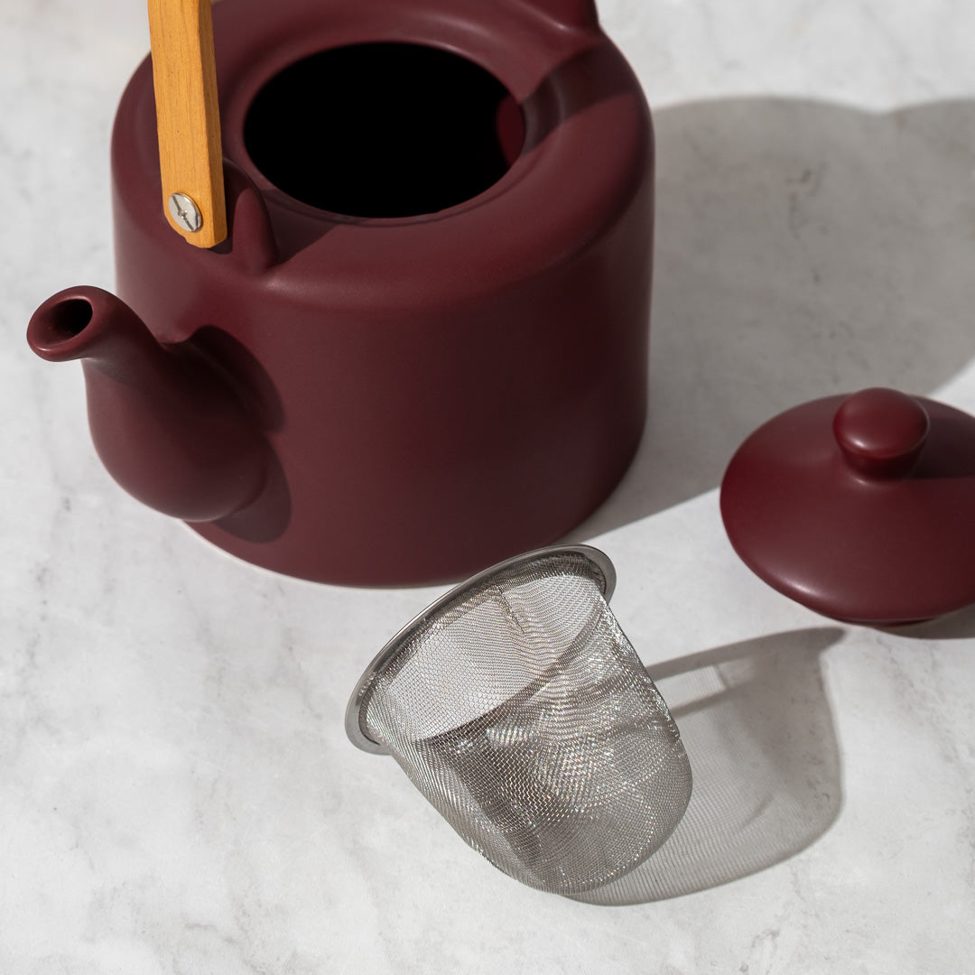 Plum Teapot with lid and infuser next to it on counter
