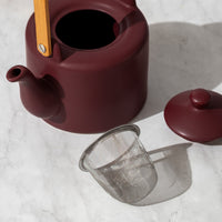 Plum Teapot with lid and infuser next to it on counter
