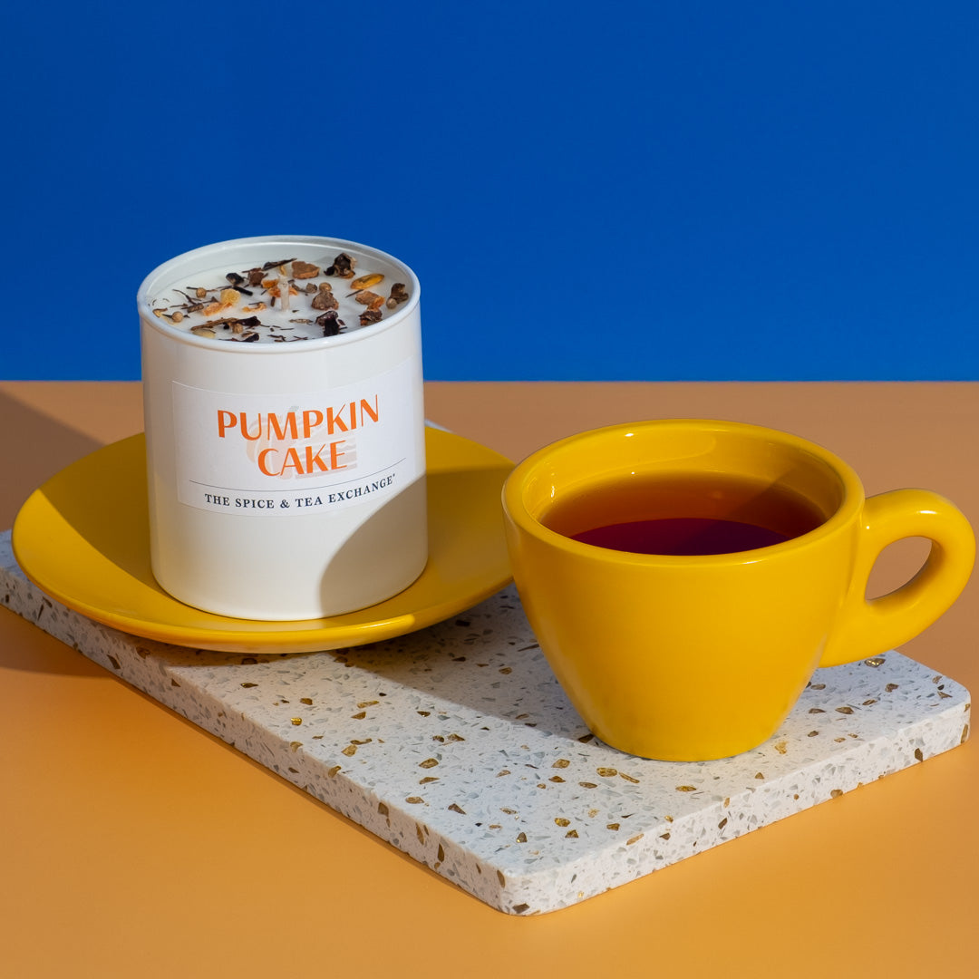 Pumpkin Cake Herbal Tea in yellow mug next to Pumpkin Cake Candle