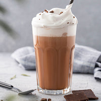 Glass of hot chocolate with whipped cream on a light surface
