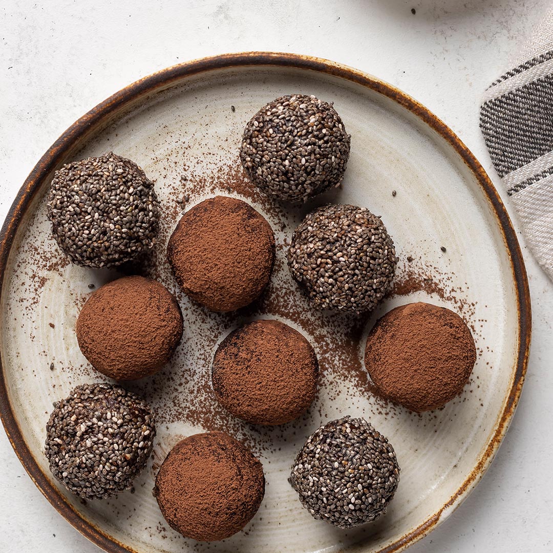 Assorted chocolate truffles on a textured ceramic plate.