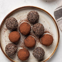 Assorted chocolate truffles on a textured ceramic plate.