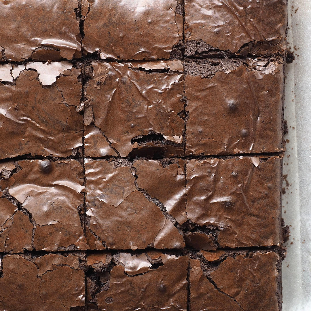 Close-up of brownies cut into squares, their crisp, shiny tops revealing a rich fudgy texture. Made with Roasted Espresso Monk Fruit Sweetener, they have a subtle coffee twist and natural sweetness.