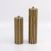 Two cylindrical striped containers, one short and one tall, standing upright on a light gray studio background. The bodies have vertical metallic gold and dark brown stripes, and each has a small silver screw cap on top.