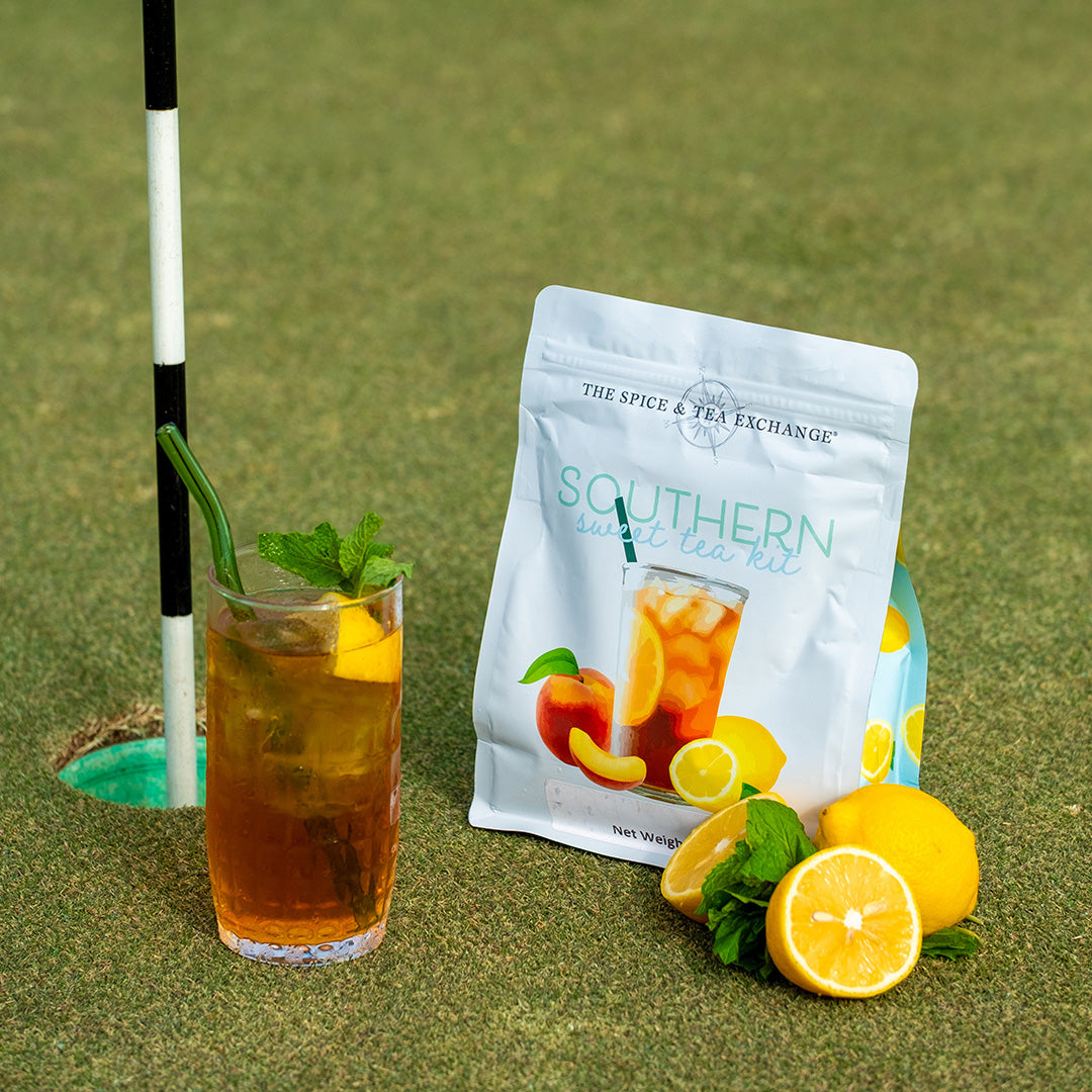 Glass of iced tea with lemon slices, a straw, and a package of 'Southern Sweet Tea Kit' on a golf turf