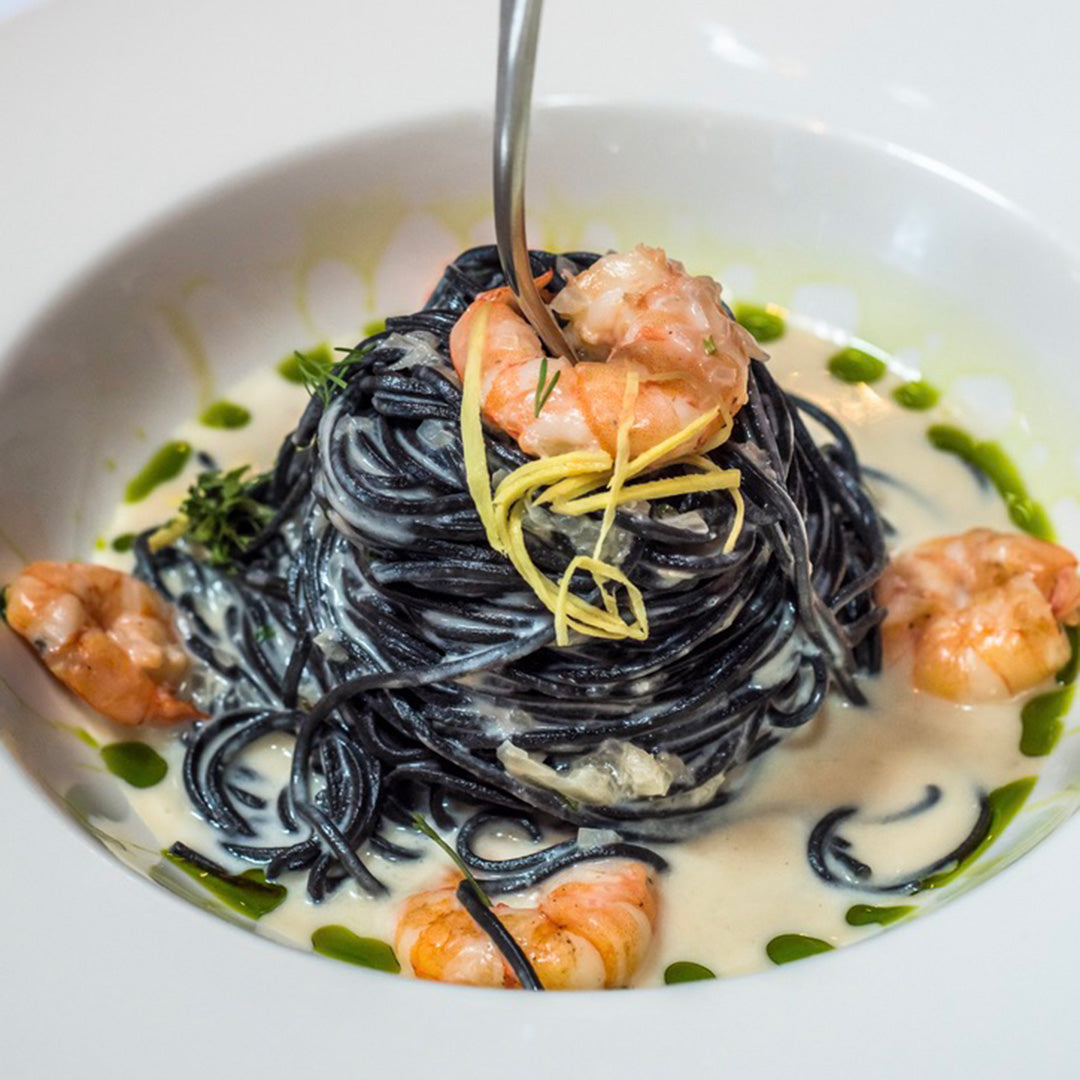 Squid ink pasta with shrimp on a white plate