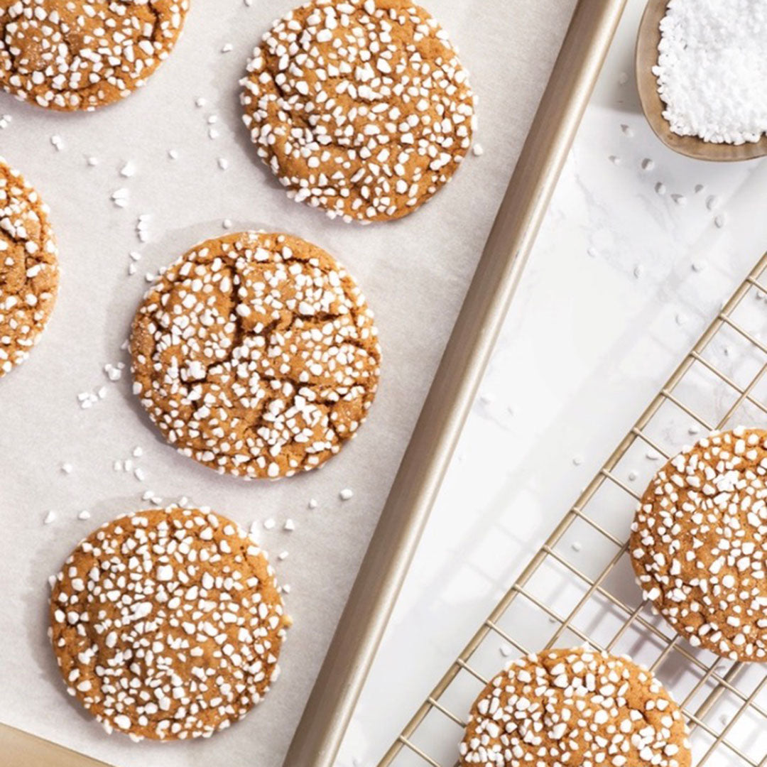 Cookies with white sprinkles on a baking sheet and cooling rack.