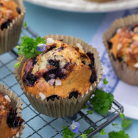 Blueberry muffin with a sprig of mint on a cooling rack