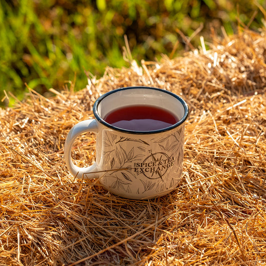 Tea mug with a floral design on a bed of straw outdoors