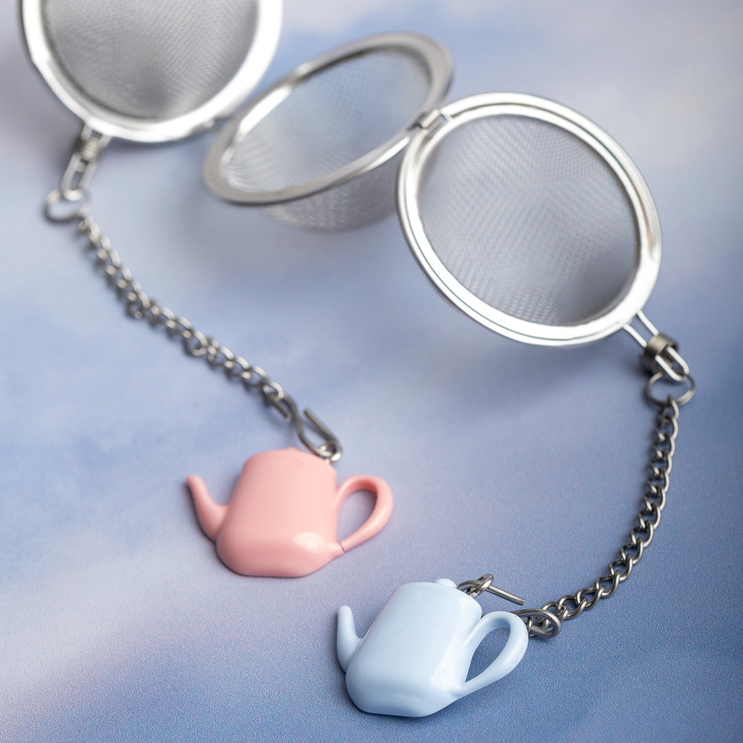 Tea infuser with pink teapot and blue cup charm on a light blue background