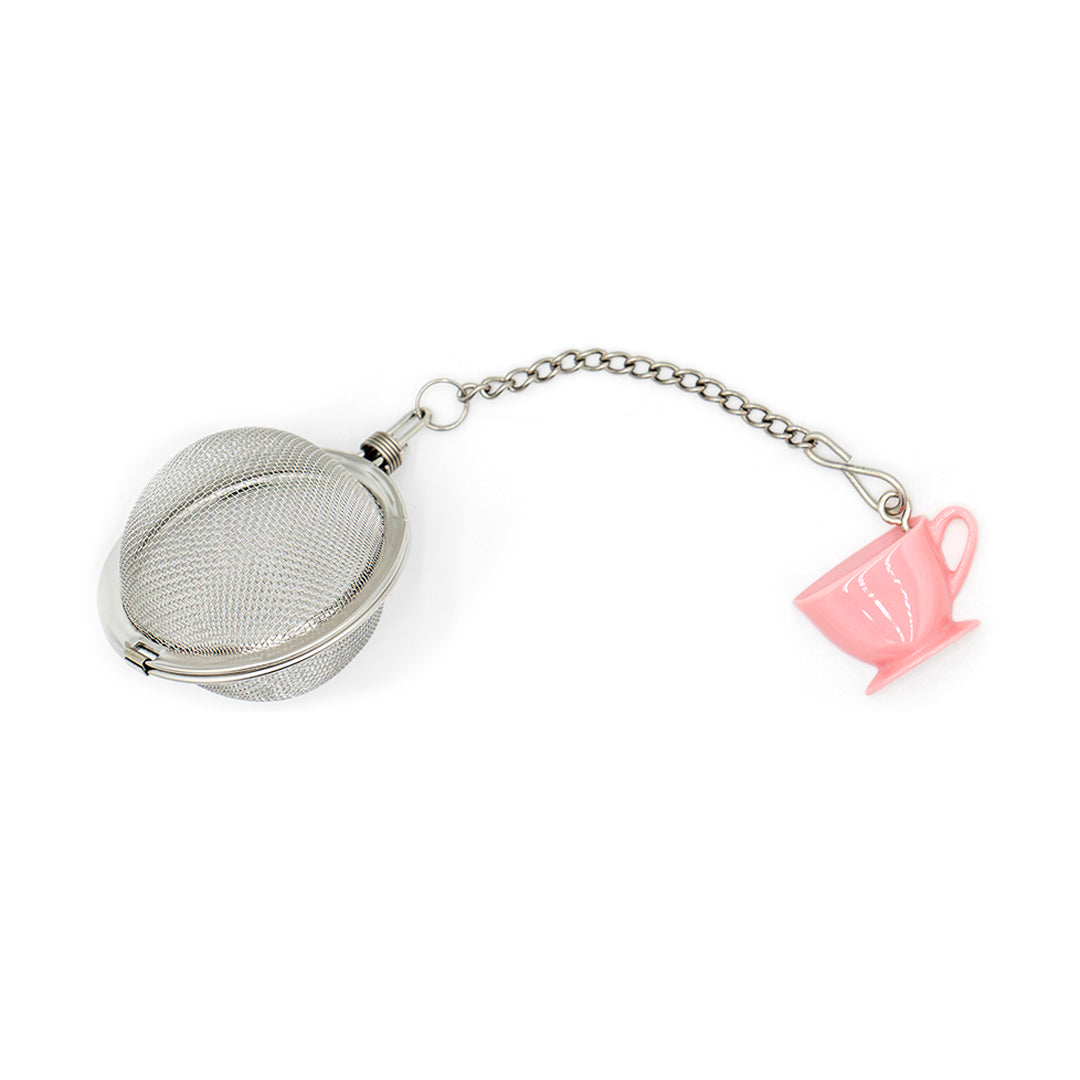 Metallic tea ball with a pink teacup charm on a white background