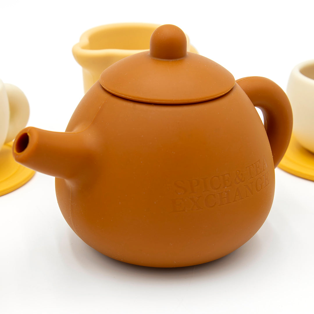 The Tiny Tea Party Toy Set features a brown teapot embossed with SPICE & TEA EXCHANGE and cream and yellow teacups—perfect for pretend play in any play kitchen, all set against a crisp white background.