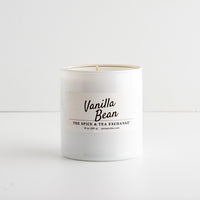 A white glass candle jar labeled 'Vanilla Bean' by The Spice & Tea Exchange, on a white background.
