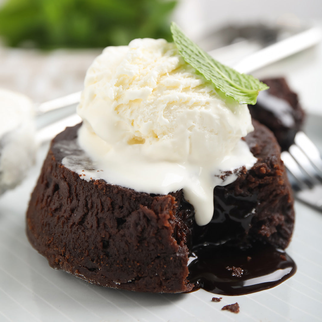 Chocolate lava cake with a scoop of vanilla ice cream on a white plate.