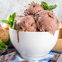 Bowl of chocolate ice cream with mint leaves on a light background