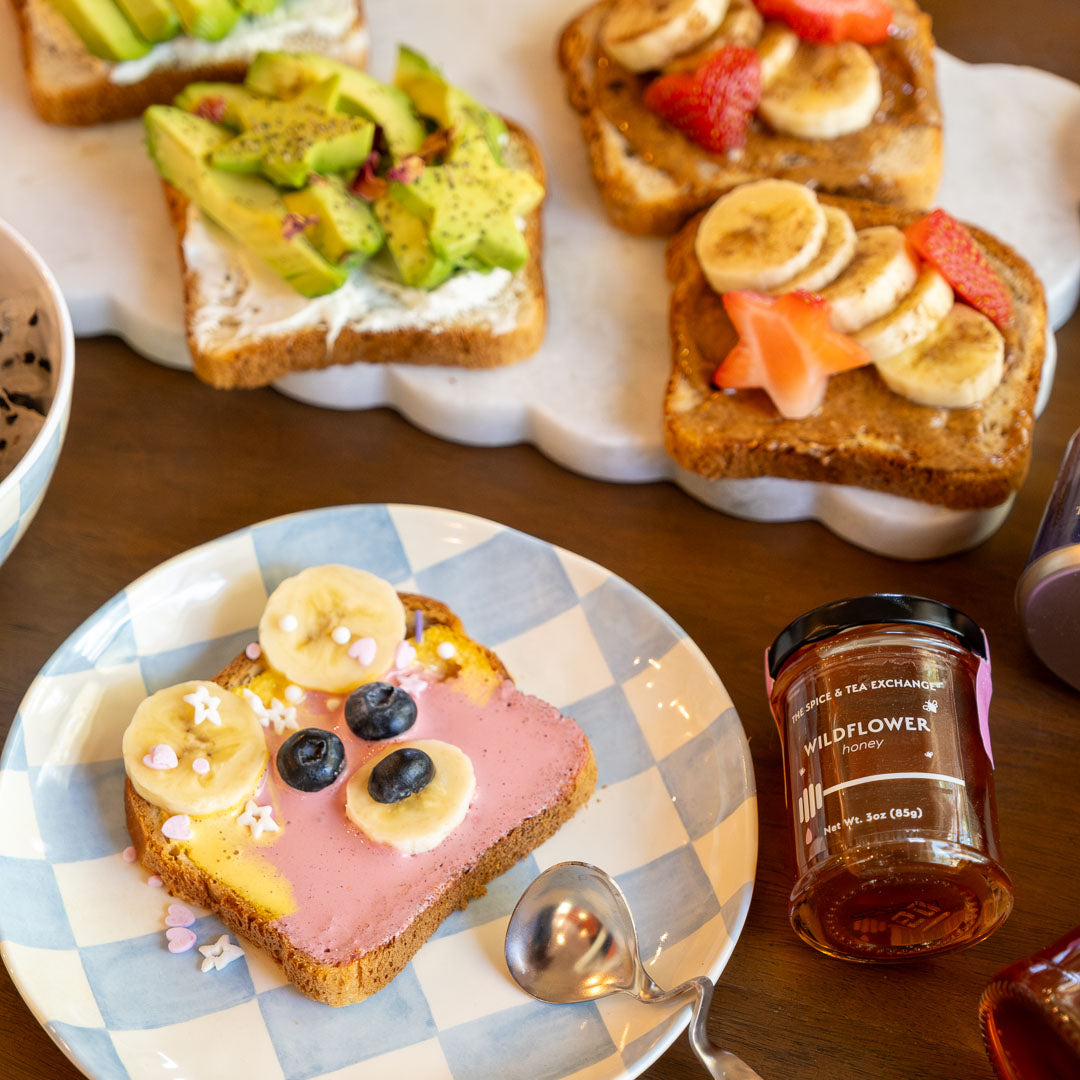 Wildflower Honey Jar next to toast with peanut butter or yogurt and various fruits